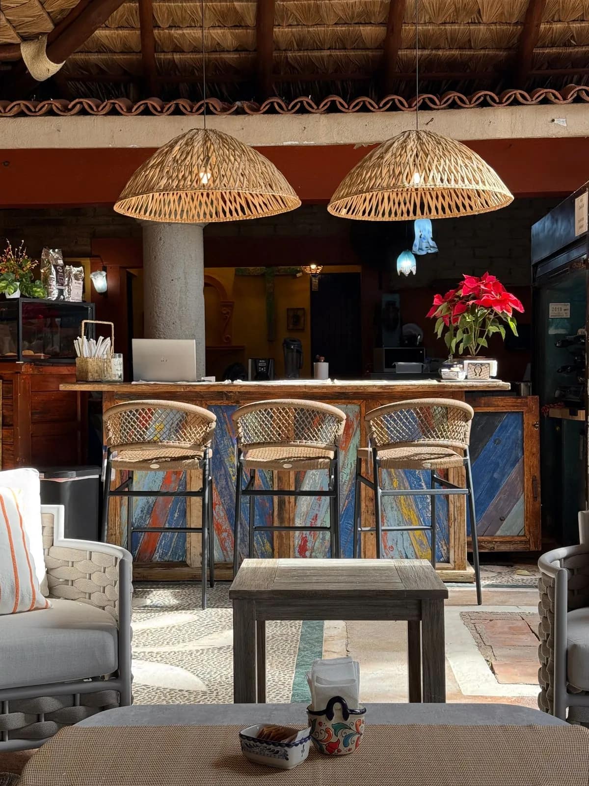 The Chalala coffee bar at Casa Bonita, woven pendant lamps over a painted wooden counter and rattan bar stools