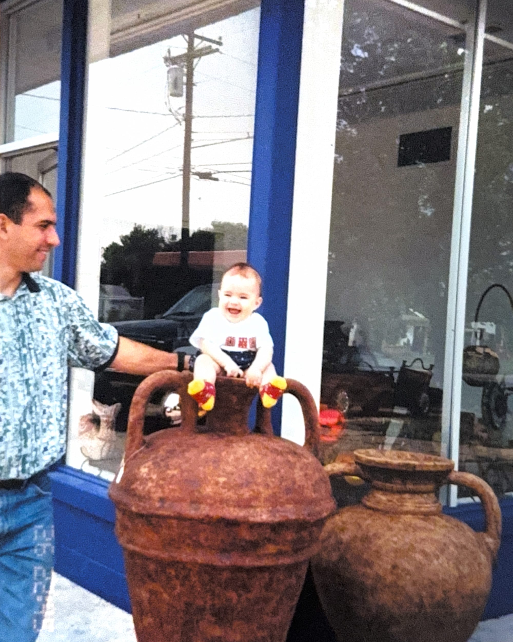An early Casa Bonita photograph: a young Jorge beside the first storefront, with a baby perched on a large clay urn