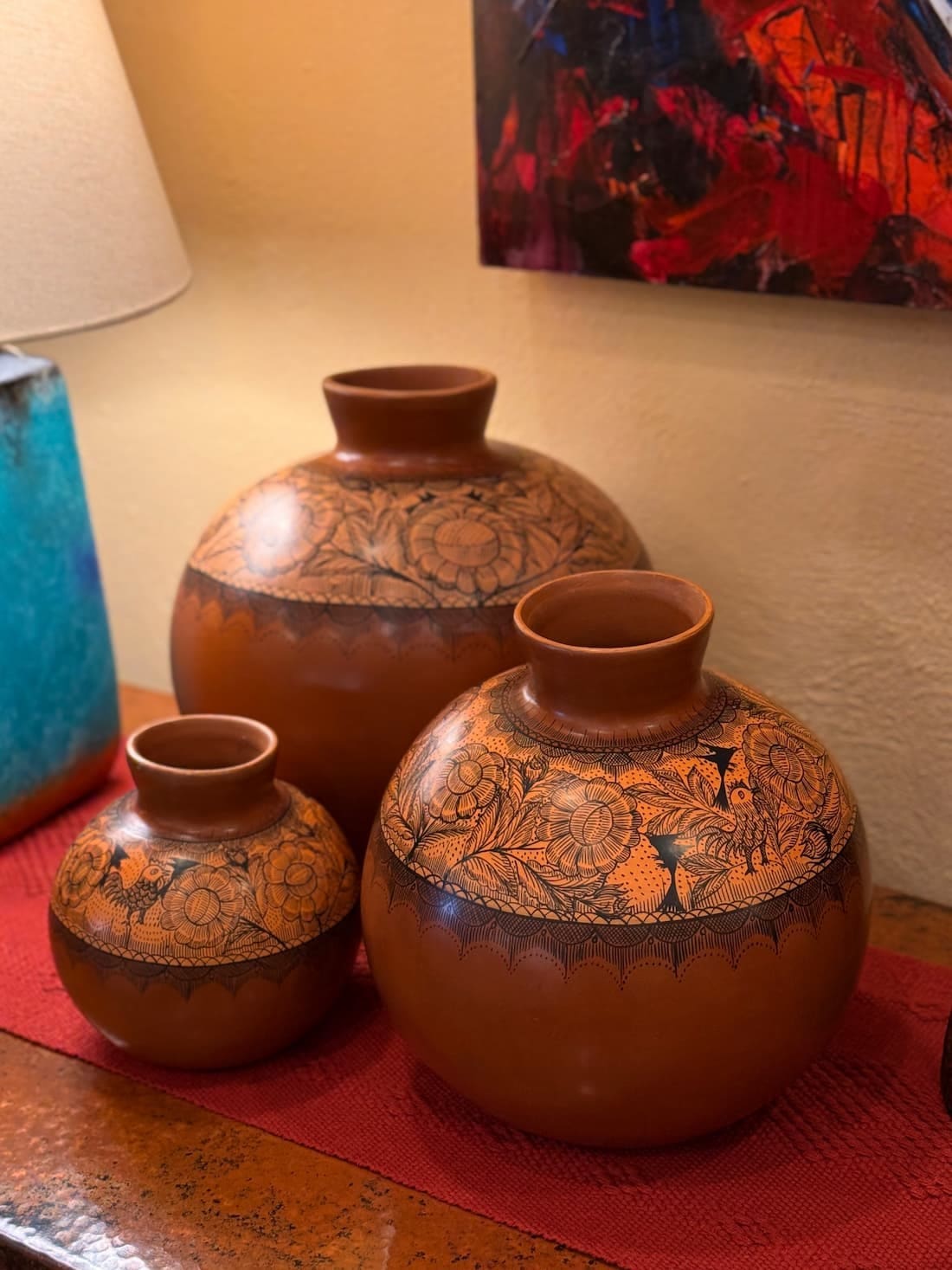 Three burnished red-brown Huáncito vessels in graduated sizes, banded with fine dark flower and bird line work