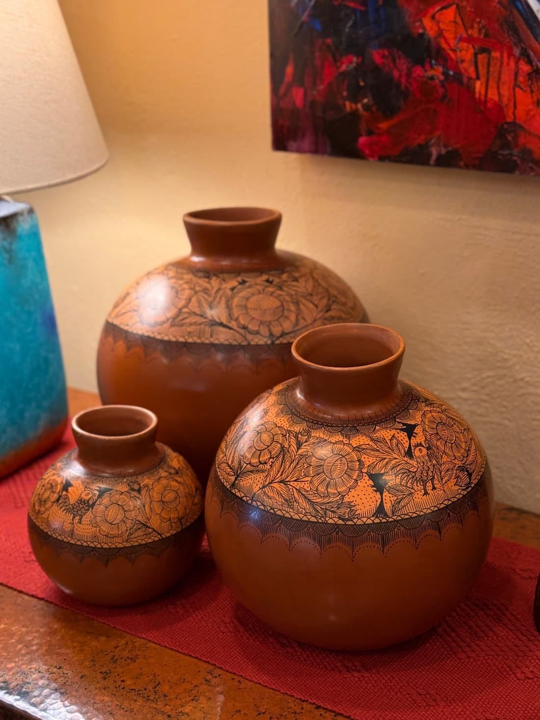 Three burnished red-brown Huáncito vessels in graduated sizes, banded with fine dark flower and bird line work