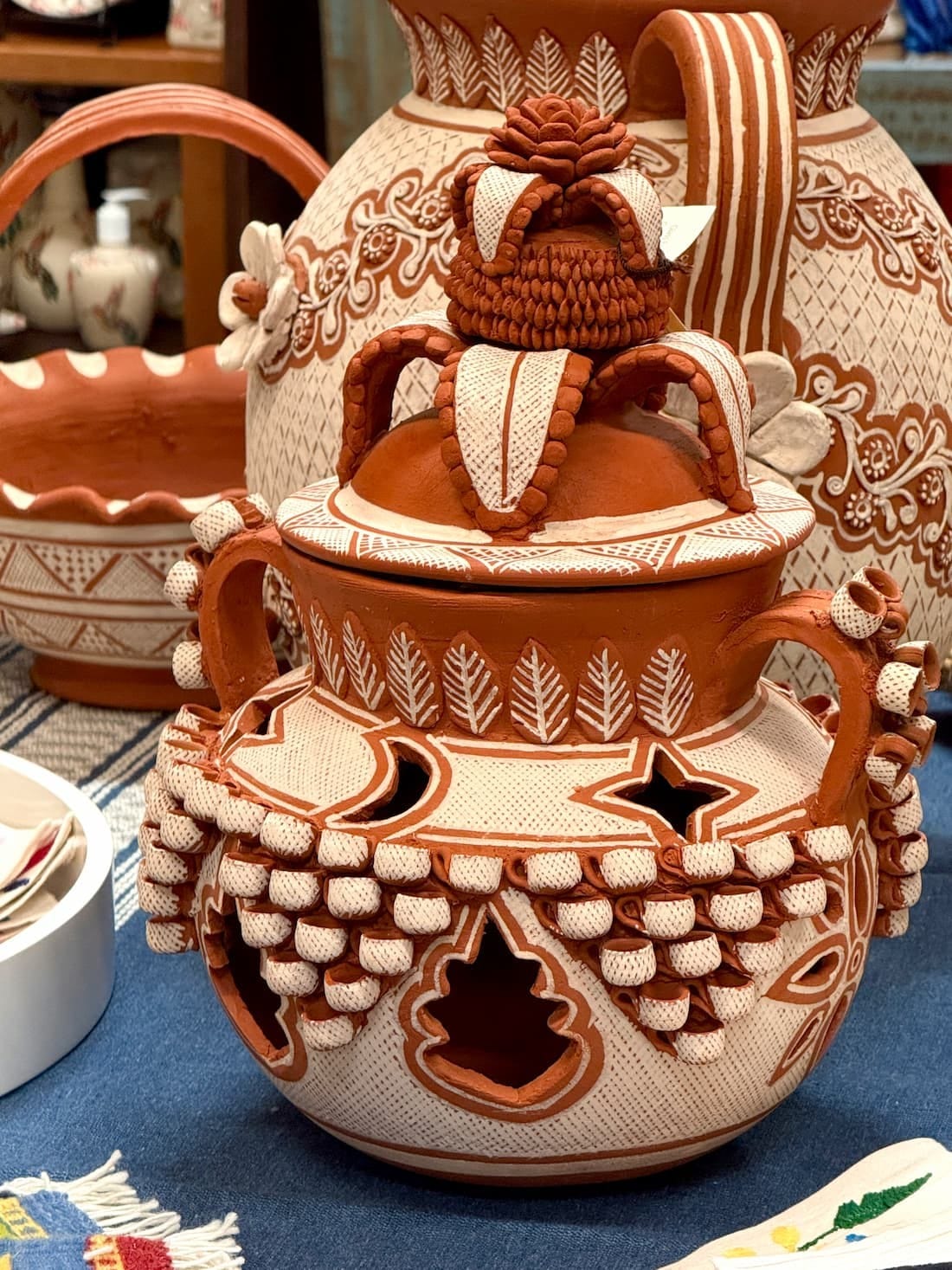 A lidded Patambán vessel in red clay, pierced with star and leaf openings and crowned with modeled fruit