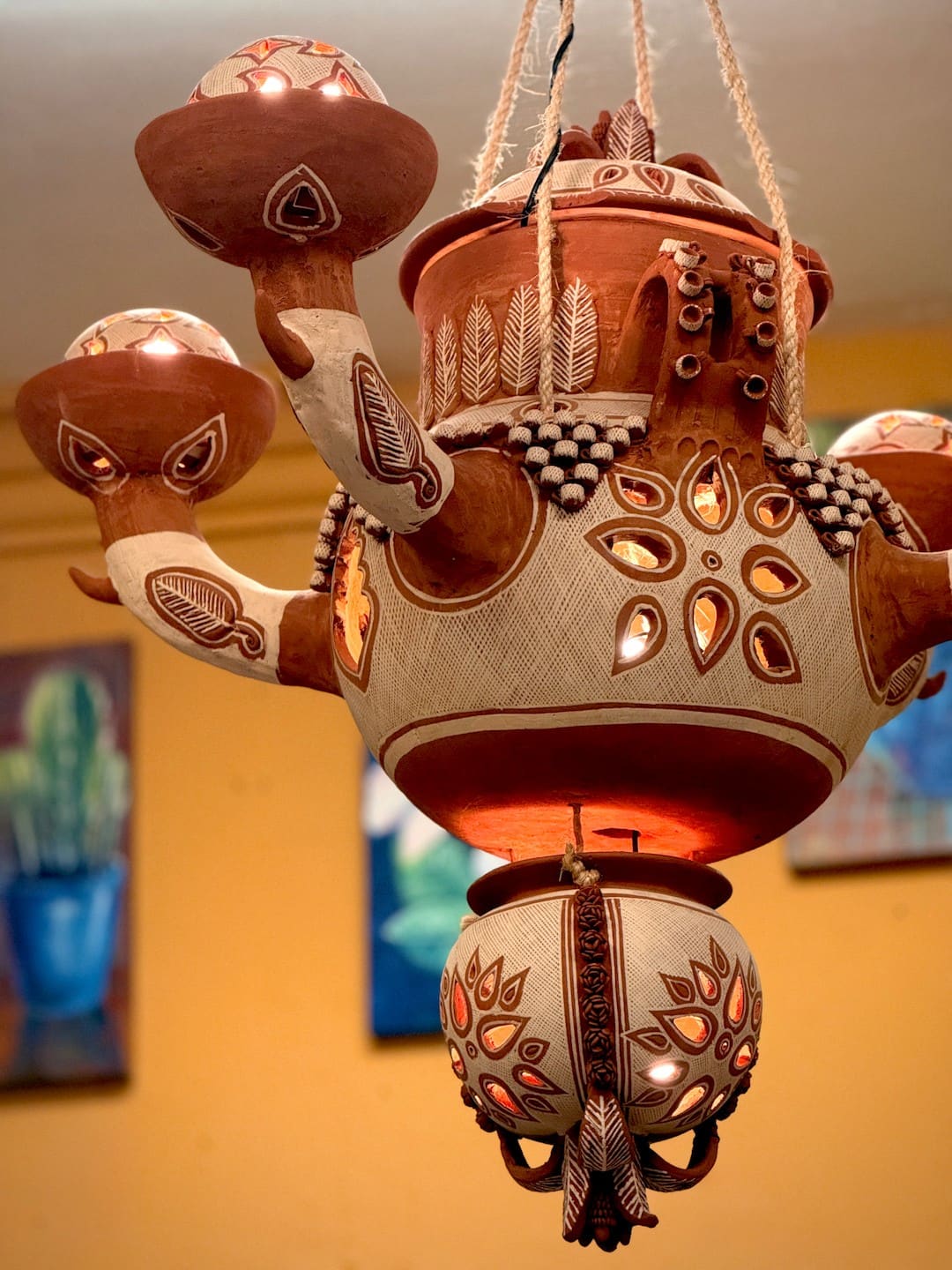 A lit red clay chandelier from Patambán, pierced and modeled with leaves and flowers